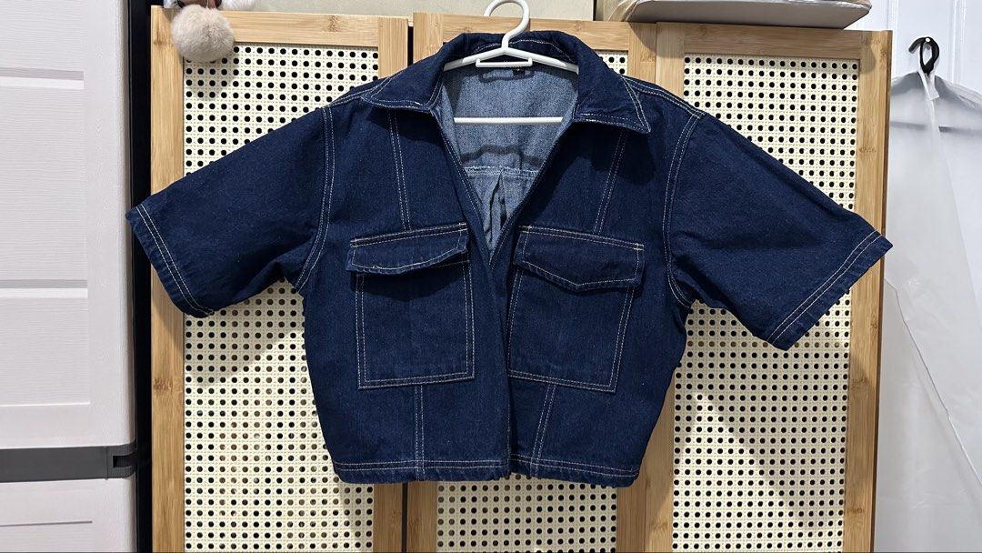 Short Sleeve Cropped Denim Jacket with Pockets (Category: Coats, Jackets and Outerwear) located in Manila. Submitted by piecesfromreg (Listing ID 1461496780, Image 1). Description: - Dark wash denim jacket - Short sleeves - Cropped fit - Two chest pockets with button closures - Contrast stitching throughout - Collared neckline.