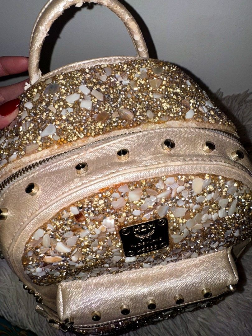 Sparkly Studded Mini Backpack (Category: Backpacks) located in Caloocan City. Submitted by mylove326 (Listing ID 1461480782, Image 2). Description: - Cute mini backpack - Covered in sparkly stones and gold studs - Features a top handle and adjustable straps - Zippers are in good working condition - Shows minor signs of wear around the edges - Perfect for a night out or adding glam to your everyday style Once lang nagamit.. Nabakbak lang kakatago.