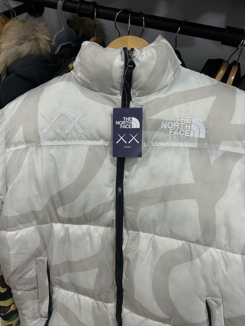 The North Face x KAWS 700 Puffer Jacket (Category: Coats, Jackets and Outerwear) located in Manila. Submitted by bodegabodega (Listing ID 1461540257, Image 2). Description: - The North Face x KAWS Collaboration Puffer Jacket - Striking White and Grey Colorway - Features iconic KAWS 'XX' motif - High-performance '700' fill power for superior warmth - Brand new with tags still attached - Perfect for stylish, cozy protection against the cold.