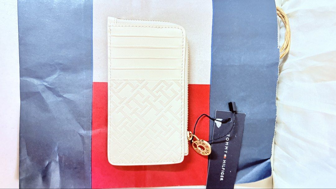 Tommy Hilfiger Card Holder Wallet (Category: Wallets & Card holders) located in Pateros City. Submitted by marifernandez (Listing ID 1461399761, Image 2). Description: - Cream colored card holder with iconic Tommy Hilfiger monogram pattern. - Features multiple card slots for easy organization. - Includes a convenient zip compartment for coins or other small items. - Stylish gold hardware detail on the zipper pull. - Comes with the original tag, e
