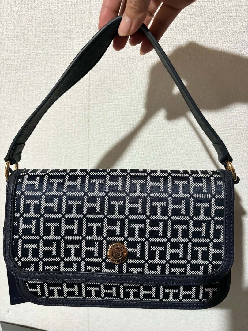 Tommy Hilfiger Monogram Shoulder Bag Navy Blue (Category: Shoulder Bags) located in Pateros City. Submitted by armcandystuff (Listing ID 1461456062, Image 1). Description: - Navy blue Tommy Hilfiger shoulder bag - Features all-over TH monogram pattern - Gold hardware detail on front closure - Includes a detachable crossbody strap - Versatile for everyday use or evening outings.