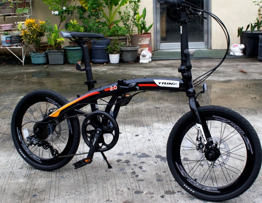 TRINX Dolphin 2.0 Folding Bicycle (Category: Bicycles) located in Manila. Submitted by jamesdela.cruz2 (Listing ID 1461326129, Image 1). Description: - TRINX Dolphin 2.0 folding bike - Sleek black frame with vibrant red and orange accents - Reliable disc brakes on both front and rear wheels - 20-inch wheels for a smooth ride - Perfect for easy commuting and convenient storage - Folds down quickly and effortlessly - more pics to share on sure buye