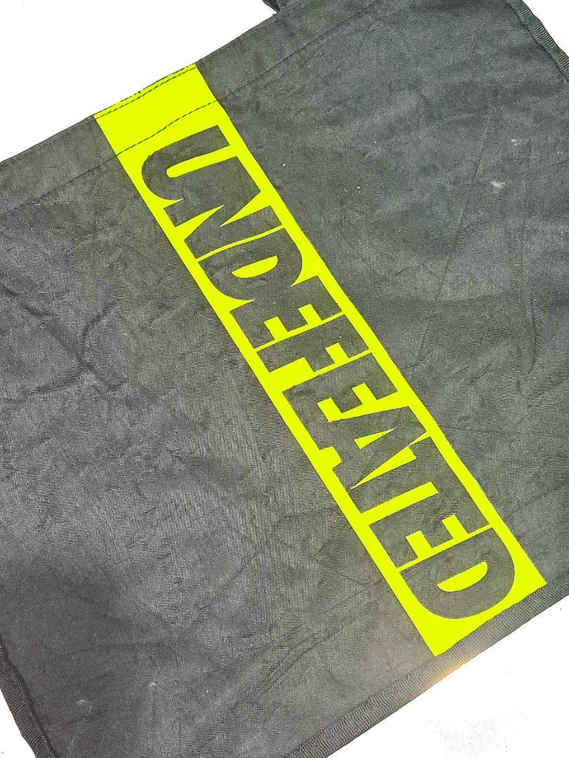 Undefeated x Starbucks Black Tote Bag (Category: Tote Bags) located in Antipolo. Submitted by saribymonica (Listing ID 1461465849, Image 3). Description: - Authentic Undefeated x Starbucks collaboration black tote bag. - Features the iconic bright yellow Undefeated logo on one side. - Showcases the Undefeated + Starbucks branding on the opposite side. - Includes a convenient small pocket inside. - Ideal for everyday use and carrying your essentia