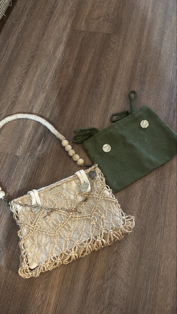 Weava Boho Macrame Shoulder Bag with Wooden Beads (Category: Shoulder Bags) located in Manila. Submitted by kimberlycryztal (Listing ID 1461538199, Image 1). Description: - Cream macrame shoulder bag - Woven design - Rope handle with wooden beads - Small metal charms on front flap - Includes a green pouch - Unique boho style.