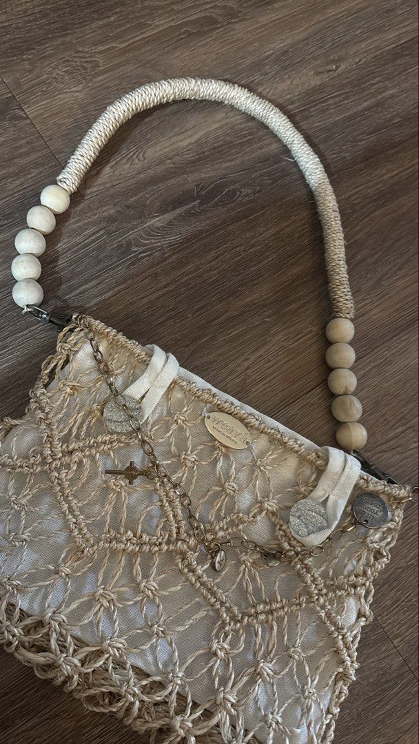 Weava Boho Macrame Shoulder Bag with Wooden Beads (Category: Shoulder Bags) located in Manila. Submitted by kimberlycryztal (Listing ID 1461538199, Image 3). Description: - Cream macrame shoulder bag - Woven design - Rope handle with wooden beads - Small metal charms on front flap - Includes a green pouch - Unique boho style.