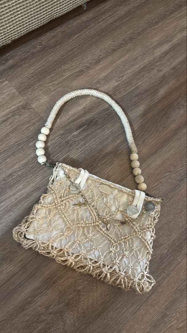 Weava Boho Macrame Shoulder Bag with Wooden Beads (Category: Shoulder Bags) located in Manila. Submitted by kimberlycryztal (Listing ID 1461538199, Image 2). Description: - Cream macrame shoulder bag - Woven design - Rope handle with wooden beads - Small metal charms on front flap - Includes a green pouch - Unique boho style.