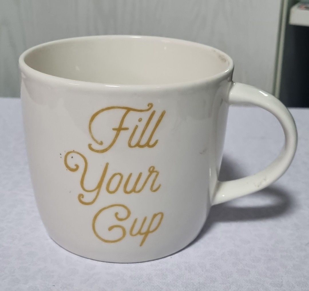 White Mug with "Fill Your Cup" Gold Text (Category: Coffee & Tea Tableware) located in Manila. Submitted by ags028705 (Listing ID 1461561157, Image 1). Description: - White ceramic mug - Gold text: "Fill Your Cup" - Ideal for morning coffee or tea - Comfortable handle - Great addition to your kitchen collection.