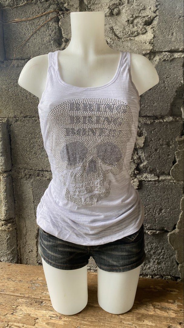 White Rhinestone Skull Tank Top (Category: Sleeveless) located in Davao. Submitted by calli_2219 (Listing ID 1461561026, Image 1). Description: - White ribbed tank top - Large rhinestone skull graphic with text on front - Stretchy and comfortable material - Versatile for casual wear or layering - Pairs well with shorts or jeans.