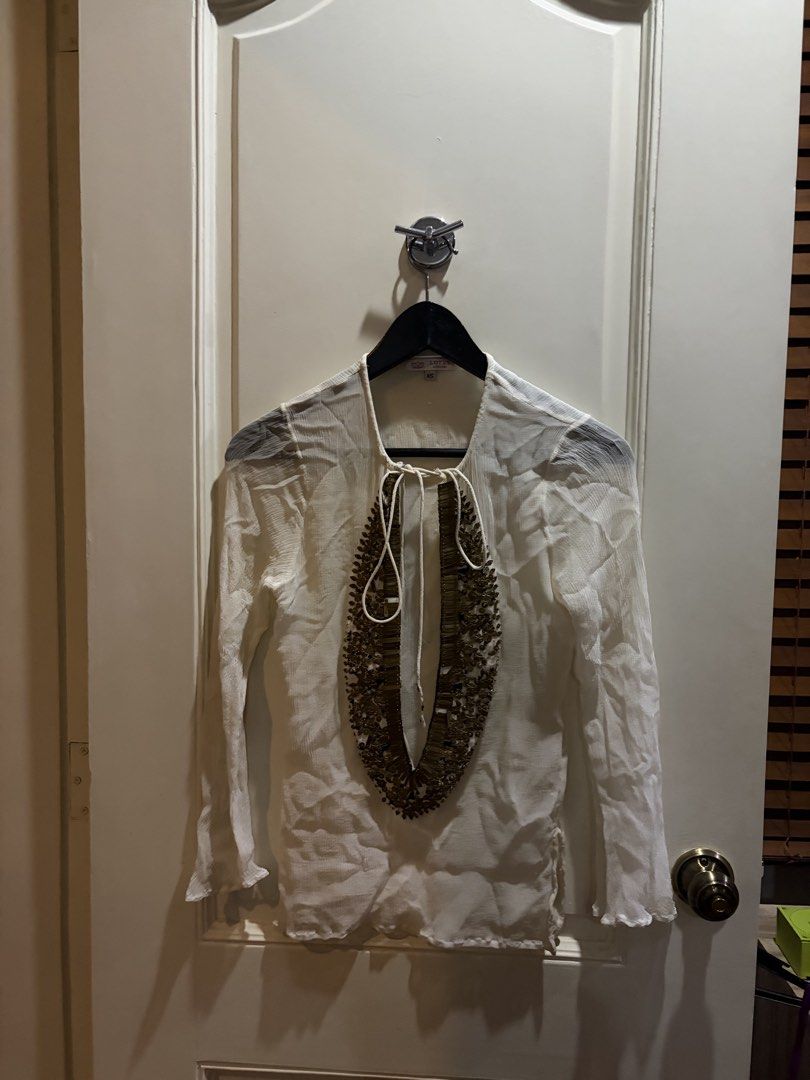 White Sheer Tunic Top with Embellished Neckline (Category: Others Tops) located in Muntinlupa City. Submitted by secondhandlove12345 (Listing ID 1461509618, Image 2). Description: - White sheer long-sleeved tunic top - V-neck with intricate gold and bead embellishments - Ties at the neck - Ruffled hem on sleeves - Lightweight and flowy material - Ideal for layering or as a beach cover-up Pick up buyer Negotiable .