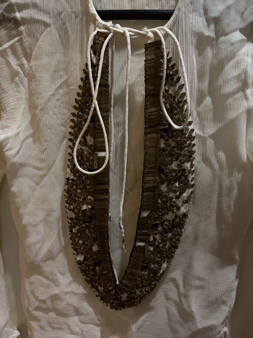 White Sheer Tunic Top with Embellished Neckline (Category: Others Tops) located in Muntinlupa City. Submitted by secondhandlove12345 (Listing ID 1461509618, Image 3). Description: - White sheer long-sleeved tunic top - V-neck with intricate gold and bead embellishments - Ties at the neck - Ruffled hem on sleeves - Lightweight and flowy material - Ideal for layering or as a beach cover-up Pick up buyer Negotiable .
