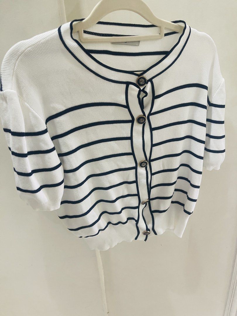 White Striped Knit Top with Gold Buttons (Category: Shirts) located in Quezon City. Submitted by prelovedluxe_ (Listing ID 1461364232, Image 2). Description: Classic and effortlessly polished white striped knit top featuring elegant contrast piping and decorative gold-tone buttons. The timeless nautical-inspired stripe pattern is complemented by a refined round neckline and button-front detail, creating a sophisticated, feminine look. Made from a