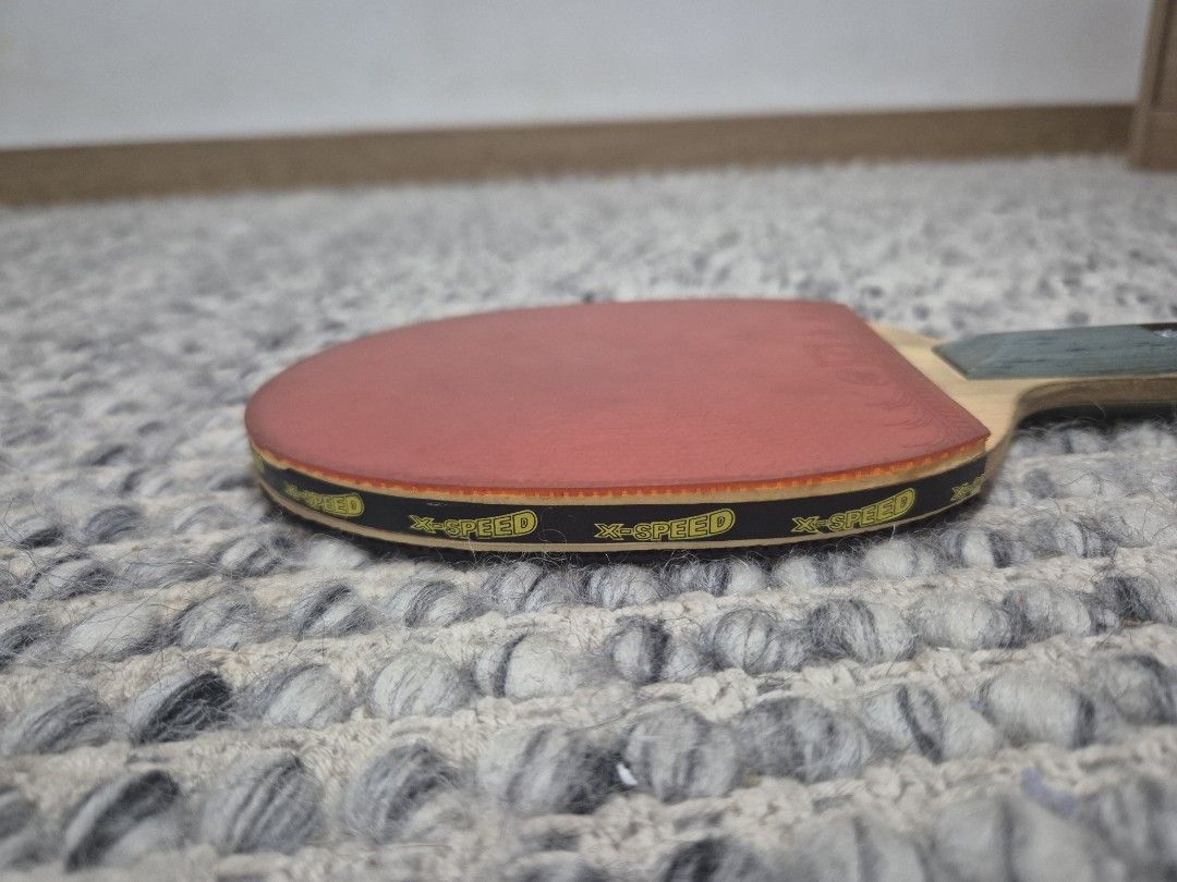 X-SPEED Table Tennis racket (Category: Other Sports Equipment and Supplies) located in Quezon City. Submitted by 53888 (Listing ID 1461487163, Image 1). Description: - X-SPEED table tennis bat - Red rubber on one side, black on the other - Handle features a blue and green design - Minor wear on the handle - Ideal for casual play.