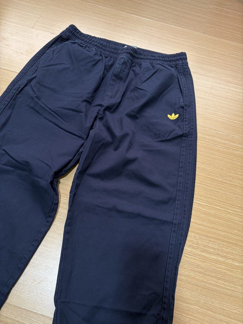 Adidas Navy Blue Track Pants with Yellow Logo (Category: Joggers) located in Makati City. Submitted by citysunset (Listing ID 1461644103, Image 2). Description: - Navy blue Adidas track pants - Length: 38.5 inches - Waist: 34 inches (stretchable) - Classic yellow Adidas trefoil logo on left thigh - Comfortable elastic waistband - Two yellow stripes down the sides - Back pocket with embroidered Adidas script logo - Ideal for casual wear or sports 