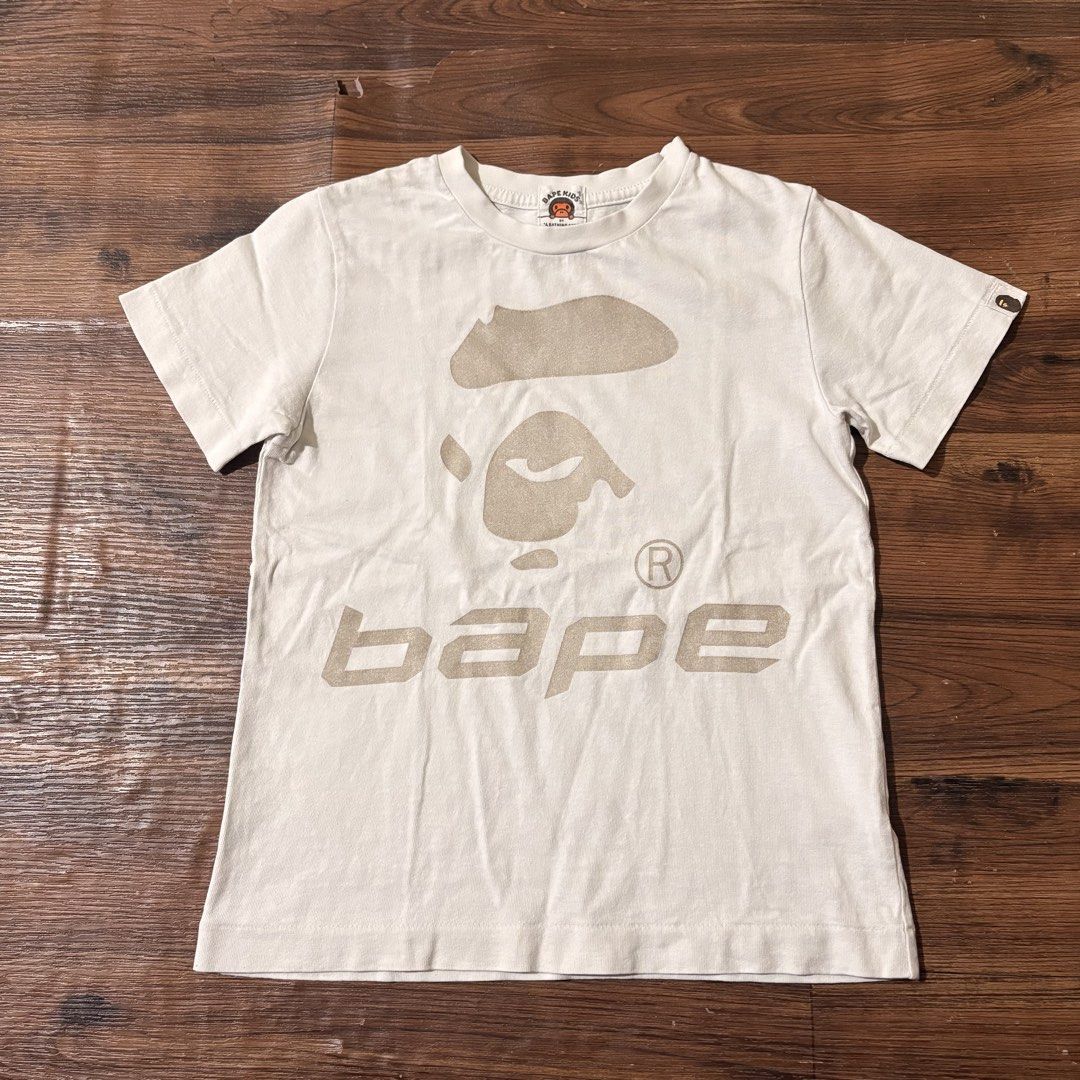 BAPE KIDS by A Bathing Ape Graphic Tee (Category: Babies & Kids Fashion) located in Cabanatuan. Submitted by house.of.thrift4 (Listing ID 1461730271, Image 1). Description: White BAPE KIDS t-shirt with iconic ape head and 'bape' logo. Authentic A Bathing Ape. Perfect for fans!.