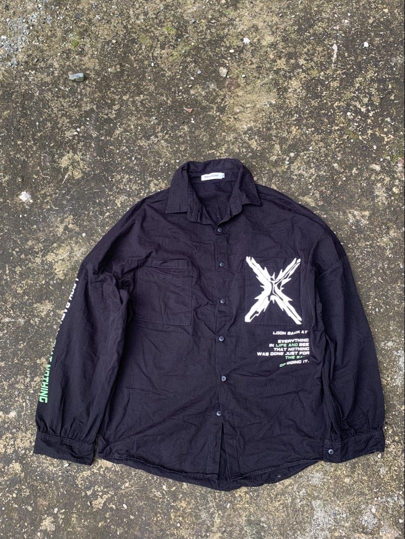 Black Graphic Button-Up Shirt with Text Print (Category: Shirts) located in Baguio. Submitted by jasthrift_ (Listing ID 1461648041, Image 1). Description: - Black long-sleeved button-up shirt - Features a graphic 'X' logo on the chest - Text printed on the left sleeve - Two chest pockets - Button closure - Estimated size: Medium to Large - Need Wash.