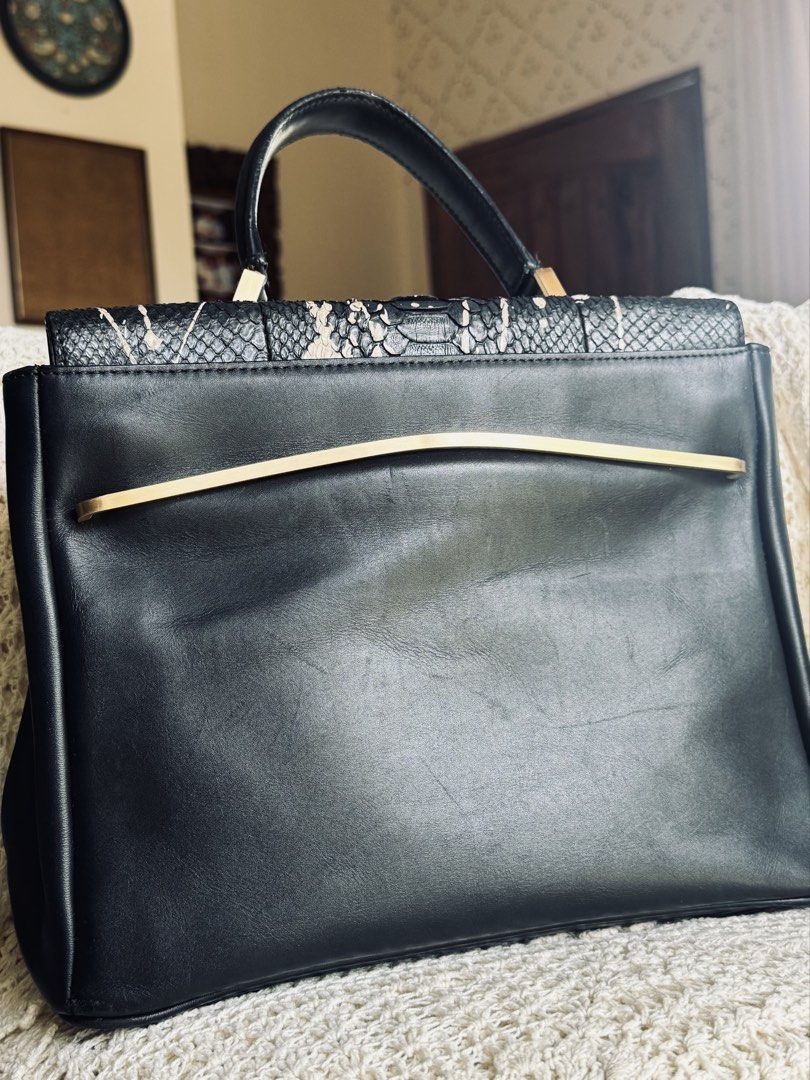 Black Leather Snake Print Handbag (Category: Luxury Bags & Wallets) located in Bacolod City. Submitted by vintage_vogue6100 (Listing ID 1461669961, Image 2). Description: - Genuine black leather handbag - Eye-catching snake print flap with unique paint splatter design - Elegant gold hardware accents - Comes with a detachable shoulder strap for versatile carrying - Spacious main compartment for all your essentials - Interior zippered pocket for se