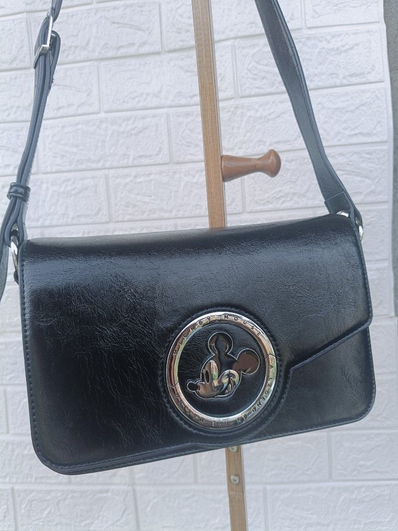 Black Mickey Mouse Crossbody Bag (Category: Cross-body Bags) located in Cavite. Submitted by j_creations18 (Listing ID 1461580209, Image 1). Description: - Cute black crossbody bag - Features a Mickey Mouse emblem - Secure magnetic snap closure - Interior zippered compartment for essentials - Adjustable strap for comfortable wear - Ideal for everyday use or a fun night out - Spacious enough for your daily necessities - Used once no damage - Dust 