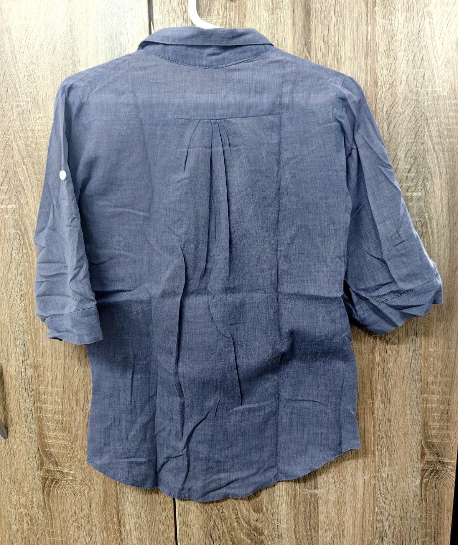 Blue Button-Up Shirt with Roll-Up Sleeves (Category: Tshirts & Polo Shirts ) located in Las Pinas. Submitted by offtonewhome (Listing ID 1461566506, Image 2). Description: - Classic blue button-up shirt - Features two chest pockets - Sleeves can be rolled up and secured with button tabs - Versatile for casual wear.