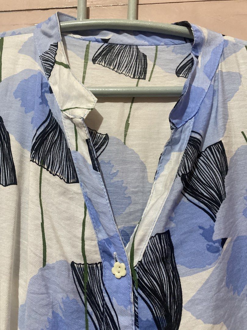 Blue Floral Button-Up Short Sleeve Top (Category: Blouses) located in Manila. Submitted by angelaay143 (Listing ID 1461775987, Image 2). Description: - White top with blue and black floral print - Short sleeves with gathered detail - Button-up front with collar - Lightweight fabric, ideal for warm weather - Versatile for casual or dressed-up looks - Needs laundry atored too long at the cabinet.