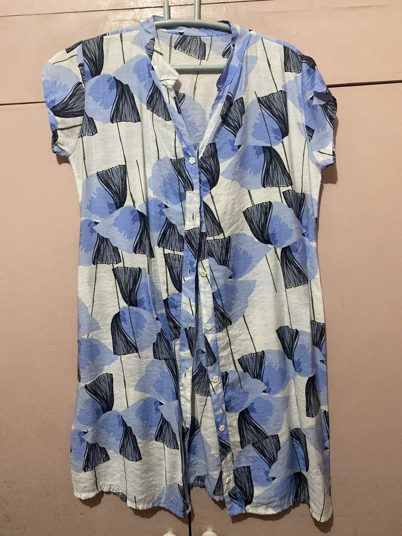Blue Floral Button-Up Short Sleeve Top (Category: Blouses) located in Manila. Submitted by angelaay143 (Listing ID 1461775987, Image 1). Description: - White top with blue and black floral print - Short sleeves with gathered detail - Button-up front with collar - Lightweight fabric, ideal for warm weather - Versatile for casual or dressed-up looks - Needs laundry atored too long at the cabinet.