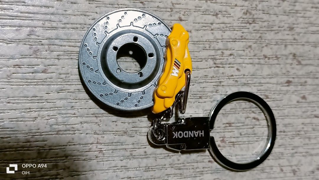 Bmw keychain (Category: Other Stationery & Craft) located in Quezon City. Submitted by Bernz (Listing ID 1461572760, Image 2). Description: This image displays a custom BMW M-Performance brake disc and caliper keychain. The piece features a miniature drilled metal brake rotor attached to a yellow brake caliper stamped with the iconic BMW ///M logo, paired with a standard chrome key ring and a BMW roundel logo base plate..