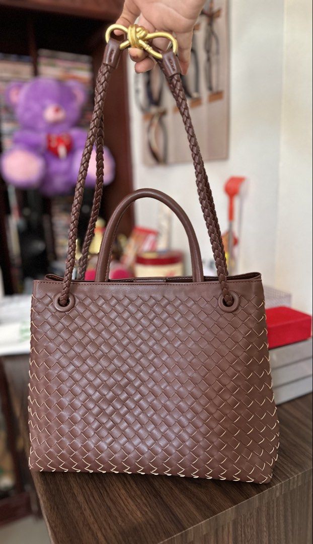 Bottega Veneta Woven Bag (Category: Luxury Bags & Wallets) located in Cebu City. Submitted by ludz_0246_2.0 (Listing ID 1461724720, Image 1). Description: - Beautiful brown woven leather handbag - Features braided handles - Chic gold knot detail at the front - Spacious interior with a zippered pocket - Intricate and well-done weaving - Versatile for everyday use or a night out - Stylish addition to any outfit.