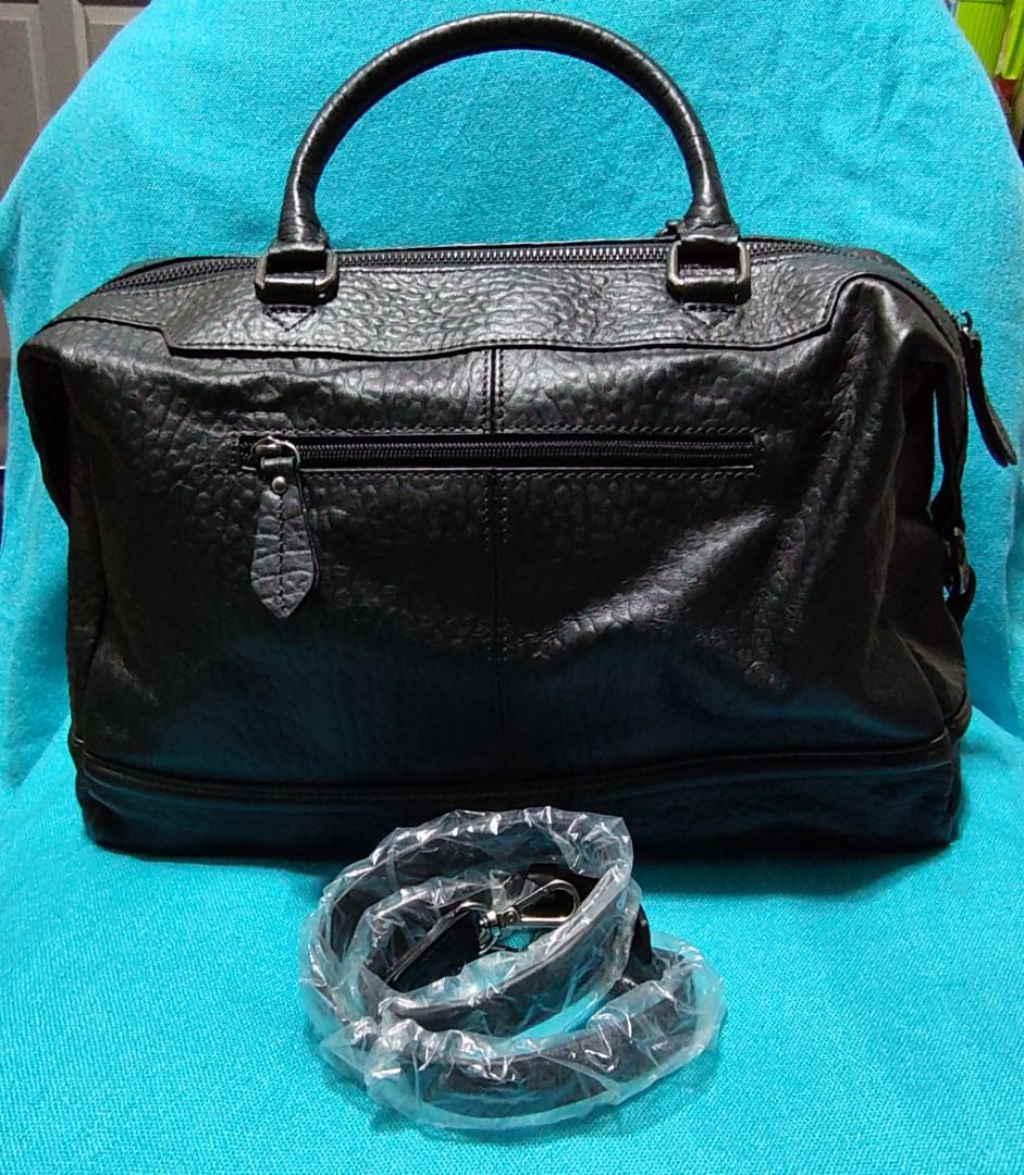 BRHAS PATI Black Leather Duffle Bag with Strap (Category: Sling Bags) located in Caloocan City. Submitted by jpmshoppe (Listing ID 1461672177, Image 3). Description: - Genuine black leather duffle bag - Textured finish for a sophisticated look - Spacious main zip compartment - Convenient exterior zip pocket - Includes a detachable shoulder strap for versatile carrying - Elegant metal hardware details - Interior tag reads "BRHAS PATI" - Ideal for 