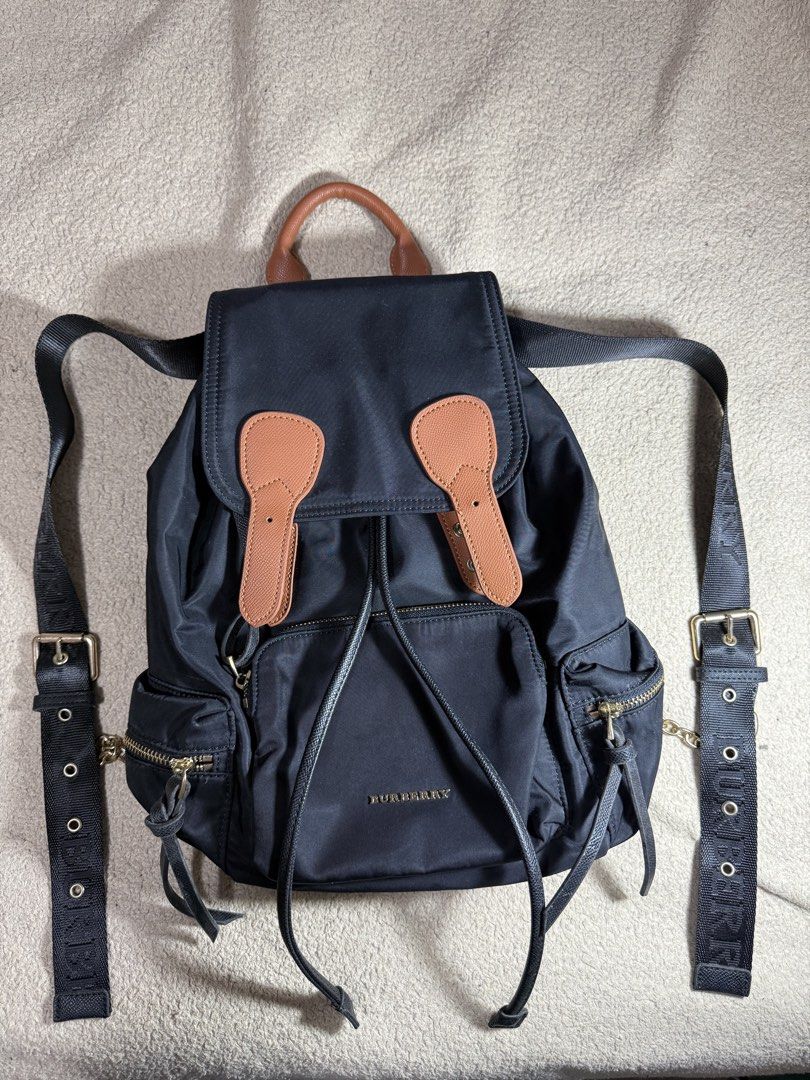 Burberry Black Nylon Backpack with Leather Trim (Category: Backpacks) located in Manila. Submitted by paulseller009 (Listing ID 1461747234, Image 1). Description: Black Burberry backpack. Nylon material with leather accents. Drawstring closure under a flap top. Multiple zip pockets on the front and sides. Adjustable shoulder straps with Burberry branding. Gold-tone hardware. Interior zip pocket and slip pockets. Great for everyday use. Issue: loc