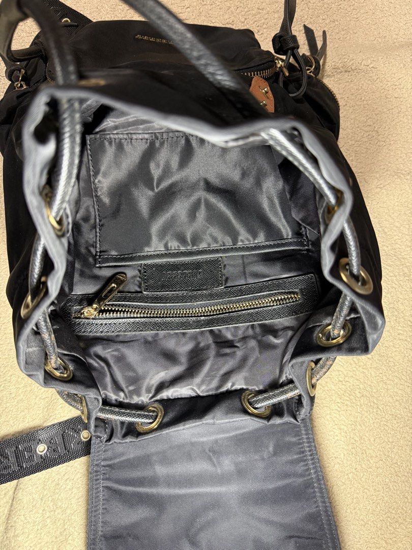 Burberry Black Nylon Backpack with Leather Trim (Category: Backpacks) located in Manila. Submitted by paulseller009 (Listing ID 1461747234, Image 3). Description: Black Burberry backpack. Nylon material with leather accents. Drawstring closure under a flap top. Multiple zip pockets on the front and sides. Adjustable shoulder straps with Burberry branding. Gold-tone hardware. Interior zip pocket and slip pockets. Great for everyday use. Issue: loc