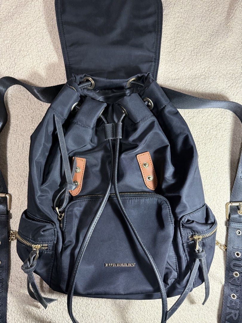 Burberry Black Nylon Backpack with Leather Trim (Category: Backpacks) located in Manila. Submitted by paulseller009 (Listing ID 1461747234, Image 2). Description: Black Burberry backpack. Nylon material with leather accents. Drawstring closure under a flap top. Multiple zip pockets on the front and sides. Adjustable shoulder straps with Burberry branding. Gold-tone hardware. Interior zip pocket and slip pockets. Great for everyday use. Issue: loc