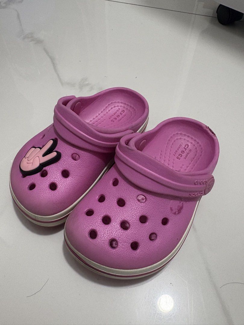 C5 (12cm) - Preloved Crocs (Category: Babies & Kids Fashion) located in Cavite. Submitted by crisalyn___ (Listing ID 1461716147, Image 2). Description: - Adorable pink Crocs for kids - Features a fun peace sign Jibbitz - Easy slip-on style for little feet - Ideal for playtime and casual outings - Soles show some wear but retain good grip.