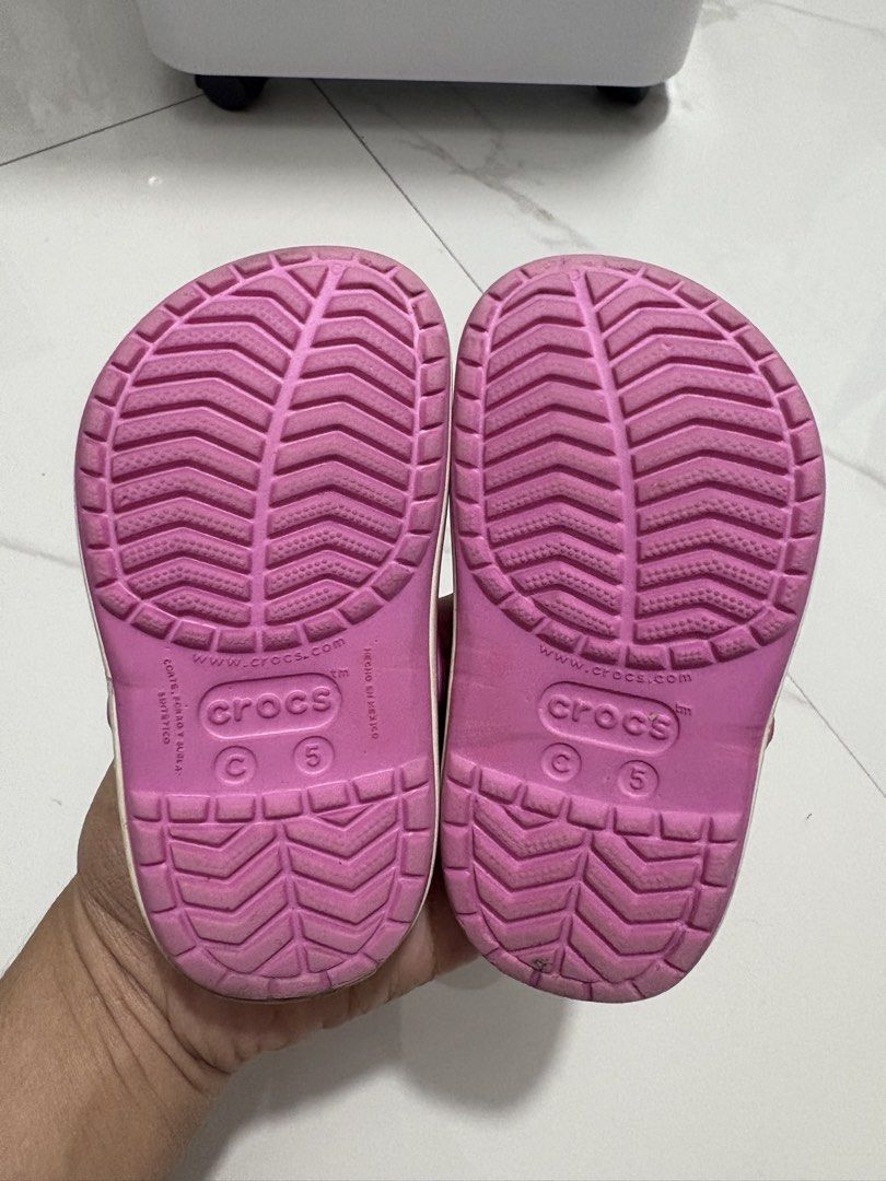 C5 (12cm) - Preloved Crocs (Category: Babies & Kids Fashion) located in Cavite. Submitted by crisalyn___ (Listing ID 1461716147, Image 3). Description: - Adorable pink Crocs for kids - Features a fun peace sign Jibbitz - Easy slip-on style for little feet - Ideal for playtime and casual outings - Soles show some wear but retain good grip.