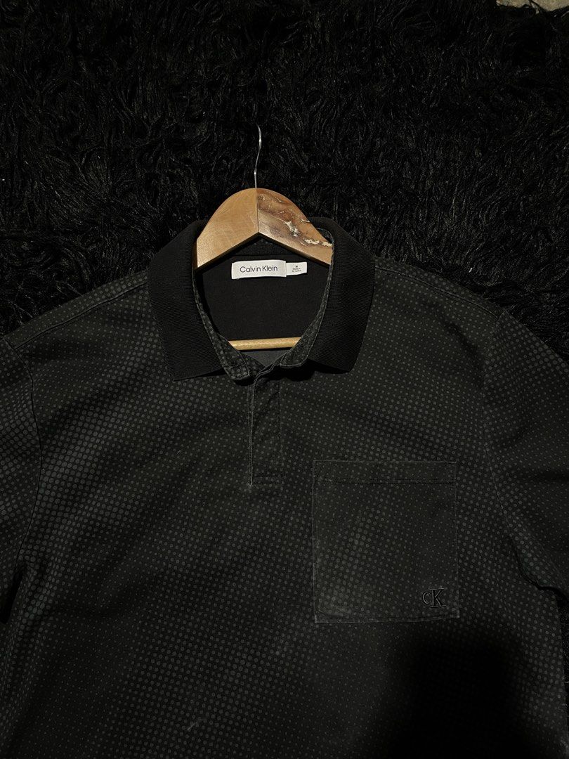 Calvin Klein Men's Black Patterned Polo Shirt (Category: Tshirts & Polo Shirts ) located in Munoz. Submitted by bb_jimbo0 (Listing ID 1461745888, Image 2). Description: - Black Calvin Klein polo shirt - Subtle all-over dot pattern - Chest pocket with small CK logo - Button-up collar - Ideal for casual wear 21 W 28 L.