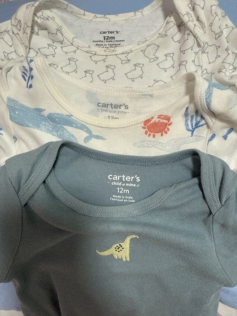 Carter's Baby Bodysuits (12M) - 3 Pack (Category: Babies & Kids Fashion) located in San Antonio. Submitted by hANNdpicked (Listing ID 1461576912, Image 2). Description: - Set of 3 Carter's bodysuits - Size: 12 months - Designs: Sheep pattern, Sea creatures (whales, octopuses, crabs), Dinosaur graphic - Color: White (sheep & sea creature), Blue-grey (dinosaur) - Sleeve length: Short-sleeved - Closure: Snap buttons at the bottom.