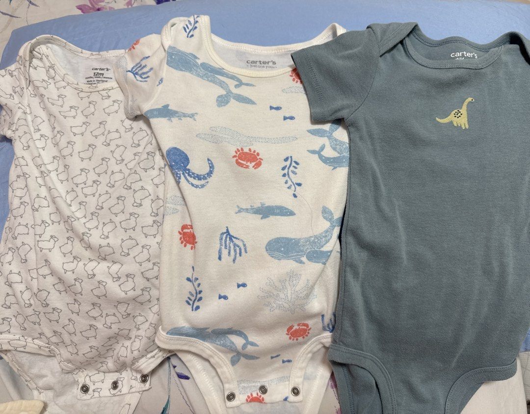 Carter's Baby Bodysuits (12M) - 3 Pack (Category: Babies & Kids Fashion) located in San Antonio. Submitted by hANNdpicked (Listing ID 1461576912, Image 1). Description: - Set of 3 Carter's bodysuits - Size: 12 months - Designs: Sheep pattern, Sea creatures (whales, octopuses, crabs), Dinosaur graphic - Color: White (sheep & sea creature), Blue-grey (dinosaur) - Sleeve length: Short-sleeved - Closure: Snap buttons at the bottom.