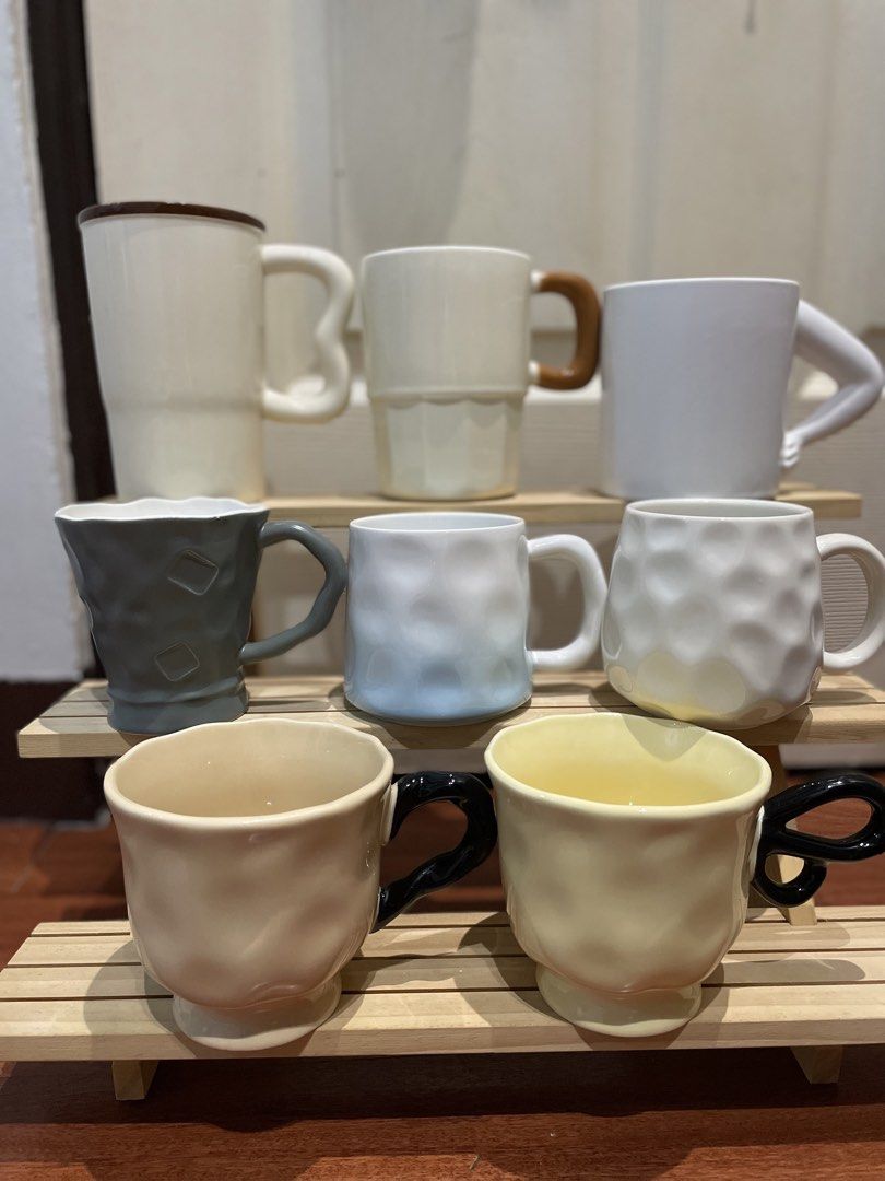 Ceramic Mugs - Various Styles and Colors (Category: Coffee & Tea Tableware) located in Quezon City. Submitted by mugs.meowph (Listing ID 1461709264, Image 1). Description: - Set of 7 ceramic mugs - Includes: tall white mug with brown rim, white mug with wooden handle, white mug with unique arm-like handle, grey mug, light blue mug, cream textured mug, yellow textured mug - Ideal for coffee or tea.