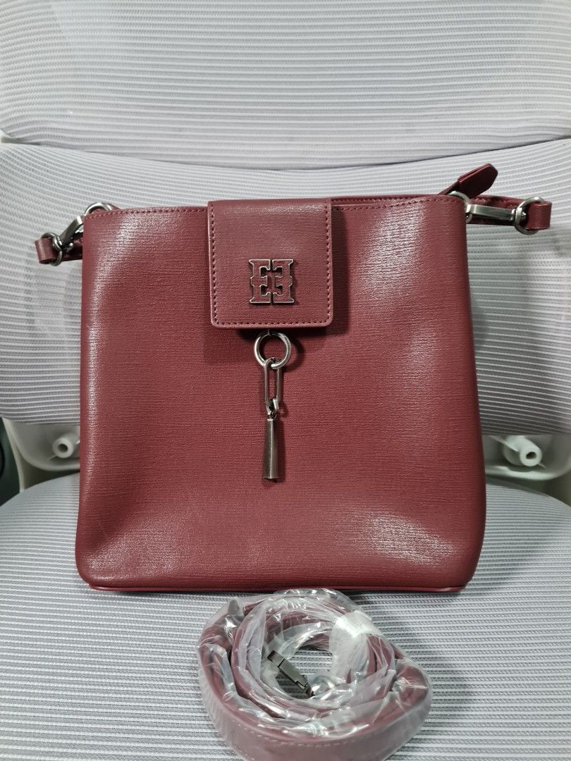 Esquirre bucket Bag (2-way) (Category: Cross-body Bags) located in Quezon City. Submitted by missmaui (Listing ID 1461780648, Image 1). Description: This is a Esquirre crossbody bag in a burgundy or wine red textured leather. Key features include: * Brand: Esquirre, identifiable by the signature metallic "EE" logo on the front magnetic closure flap. * Style: Crossbody or shoulder bag with a square-structured silhouette and a removable adjustable 