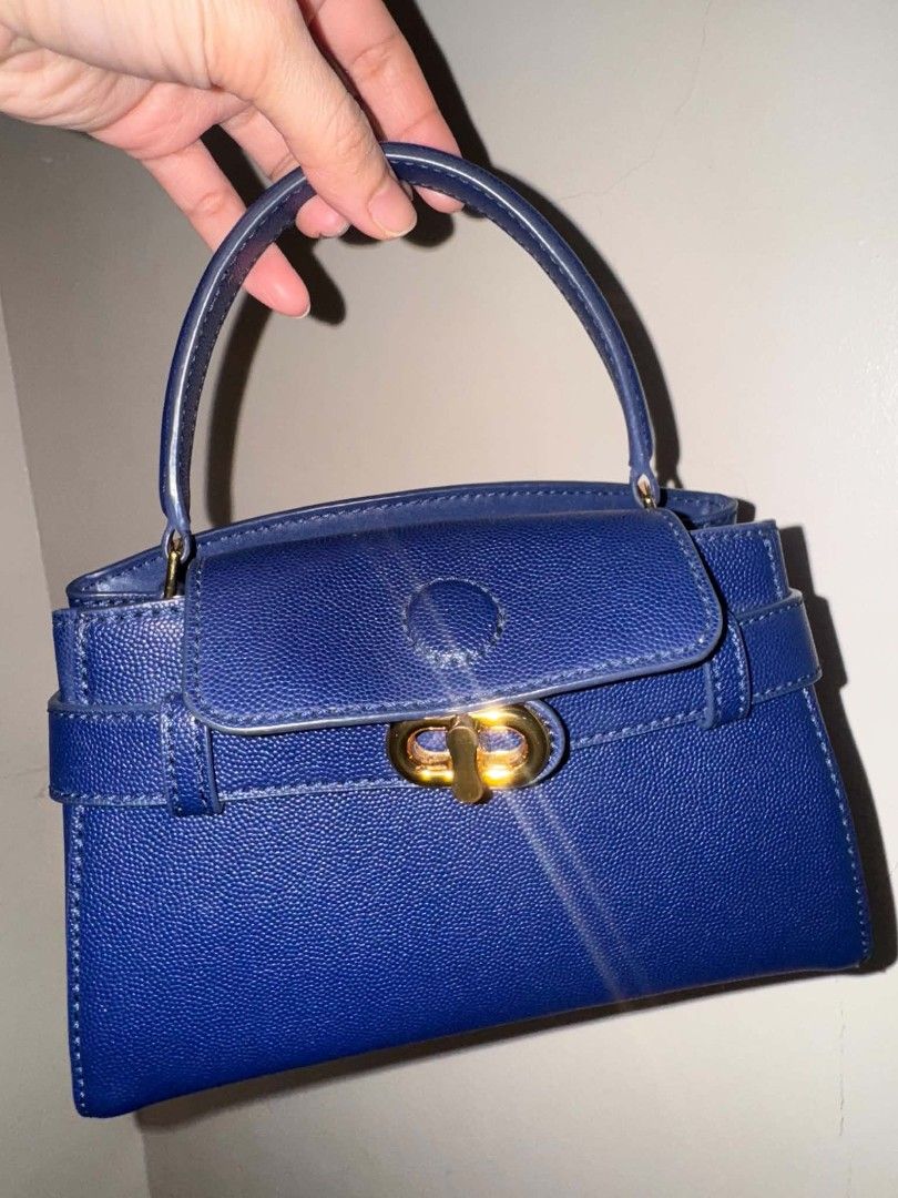 Charles & Keith Navy Blue Top Handle Bag with Strap (Category: Luxury Bags & Wallets) located in Pasay City. Submitted by pepper1997 (Listing ID 1461785278, Image 1). Description: - Navy blue top handle bag - Gold clasp closure - Detachable shoulder strap included - Embossed 'CHARLES & KEITH' logo on back - Textured leather-like material - Versatile for everyday or special occasions.