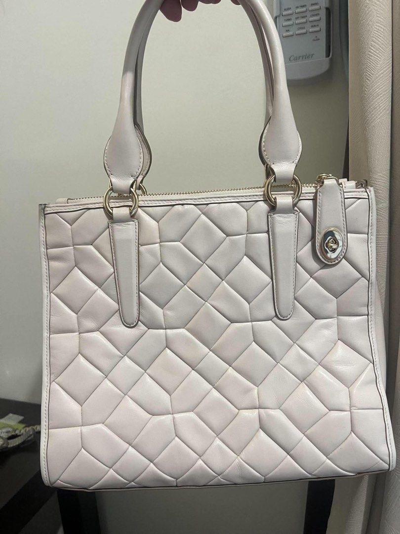 Coach Quilted Leather Tote Bag (Category: Luxury Bags & Wallets) located in Las Pinas. Submitted by tati_finds (Listing ID 1461663998, Image 2). Description: - Creamy white Coach tote bag - Unique geometric quilting all over - Gold hardware details - Top zip closure - Front pocket with turn-lock closure - Four protective metal feet on the bottom - Comfortable handles for easy carrying - Perfect stylish everyday bag.