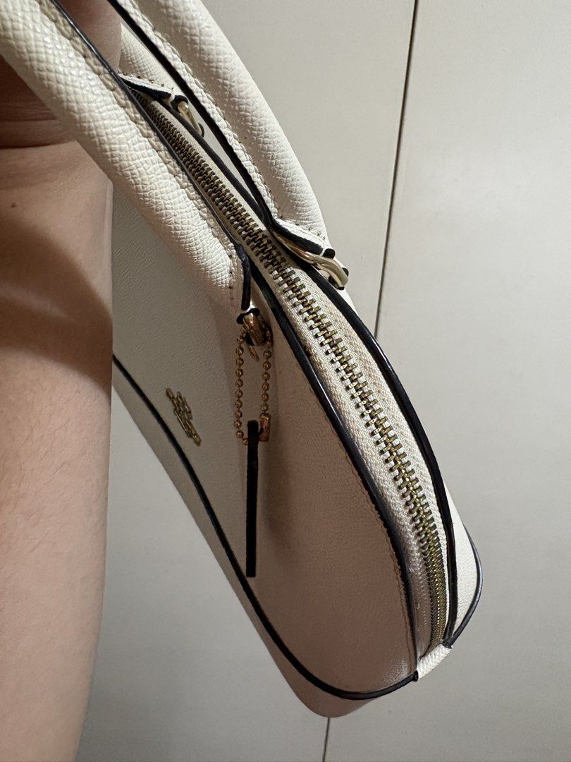 Coach White Leather Dome Satchel Handbag (Category: Luxury Bags & Wallets) located in Caloocan City. Submitted by anneicaro63490 (Listing ID 1461745687, Image 3). Description: - White Coach dome satchel - Textured leather - Gold hardware details - Top handles - Zipper closure - Includes Coach hangtag - Ideal everyday bag, fits essentials Well used but well cared. Signs of usage in the zipper area but not so noticeable. Got this for 10k sa pasabuy
