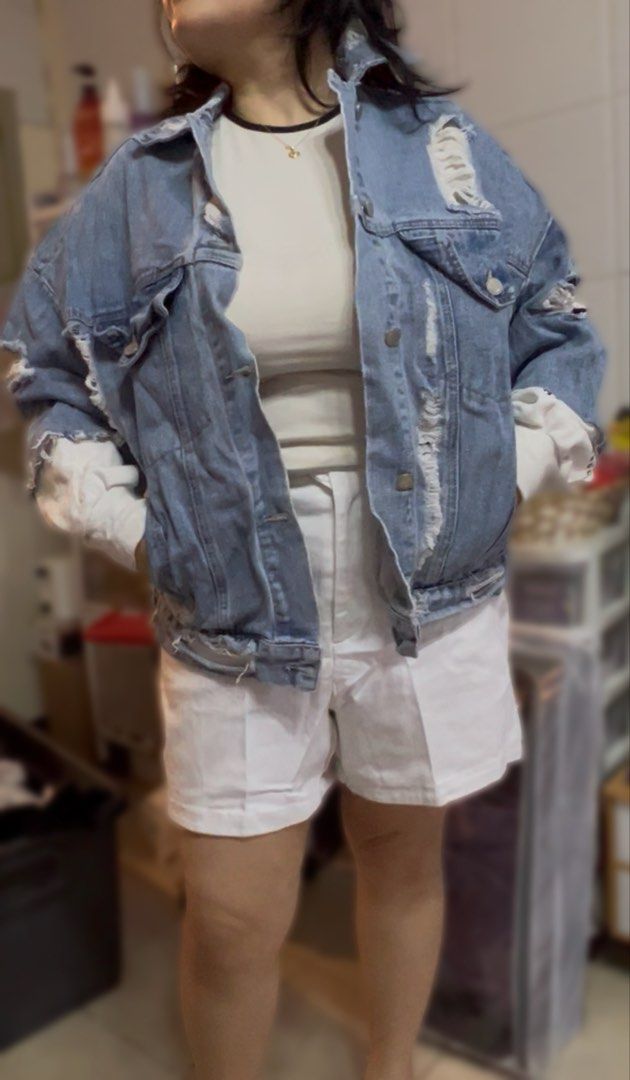 Distressed Denim Jacket with White Sleeve Inserts (Category: Coats, Jackets and Outerwear) located in Surigao. Submitted by boonz71_1971 (Listing ID 1461709345, Image 1). Description: Declutter Sale for women - Width 24” Length 20” - Oversized distressed denim jacket - Features ripped details on front and back - White long sleeves with black text print at cuffs - Unique button closure at the back - Ideal for layering - Pairs well with shorts or j