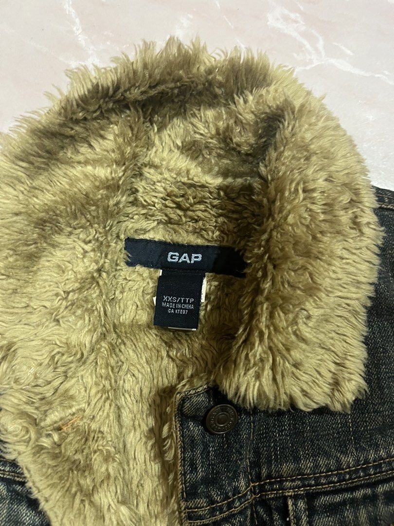 GAP Denim Vest with Fur Lining (Category: Sleeveless) located in Tabuk. Submitted by collectors_thrift_shop (Listing ID 1461636676, Image 2). Description: - GAP dark wash denim vest - Warm fuzzy fur lining and collar - Button-up front closure - Two chest pockets - Sleeveless design - Size XXS/TTP - Ideal for layering in cooler weather.