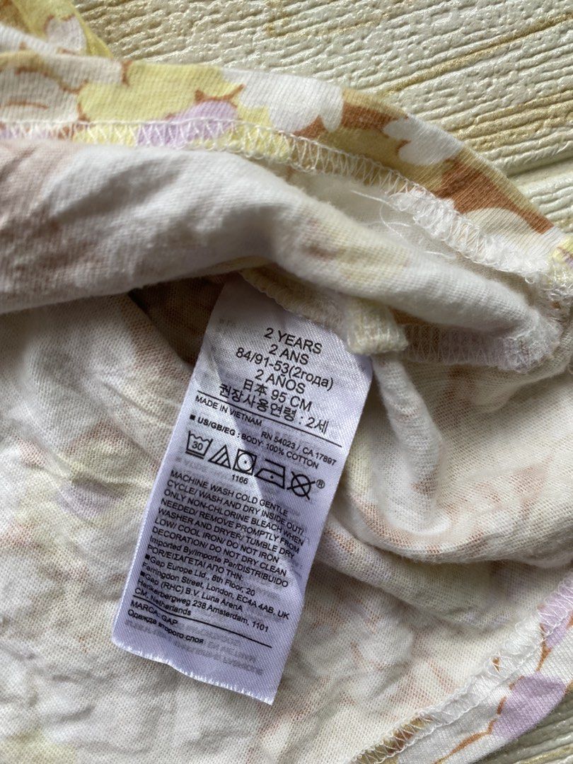 Gap floral dress (Category: Babies & Kids Fashion) located in Cebu City. Submitted by yjainani (Listing ID 1461649436, Image 3). Description: featuring a vibrant yellow, white, and purple floral pattern with a bold purple GAP logo across the chest..