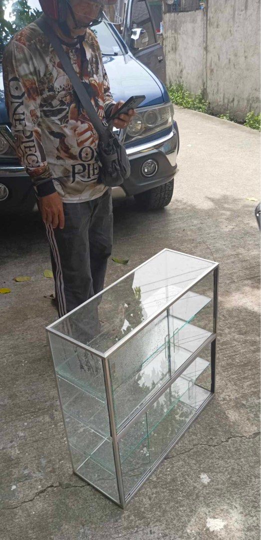 Glass Display Cabinet with Metal Frame (Category: Shelves, Cabinets & Racks) located in Manila. Submitted by aaaeina (Listing ID 1461768916, Image 1). Description: - 24x24 inches & 9” width. - NO ISSUES. Good as new. - Sleek glass display cabinet with a durable metal frame. - Two spacious shelves for ample storage or showcasing your items. - Clear glass panels offer excellent visibility. - Wrapped in cling wrap. PM for more pictures. CUBAO Locati