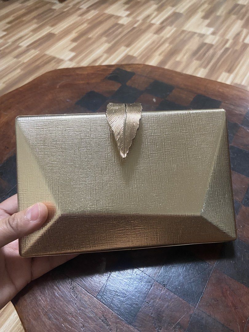 Gold Leaf Clutch Bag with Chain (Category: Clutches) located in Quezon City. Submitted by emjen (Listing ID 1461562787, Image 2). Description: - Chic gold clutch bag - Unique leaf clasp design - Detachable gold chain strap for versatility - Sleek black interior - Comes with a stylish pink and maroon striped dust bag - Ideal for parties, weddings, and special events Nearby BULACAN and QC area only.