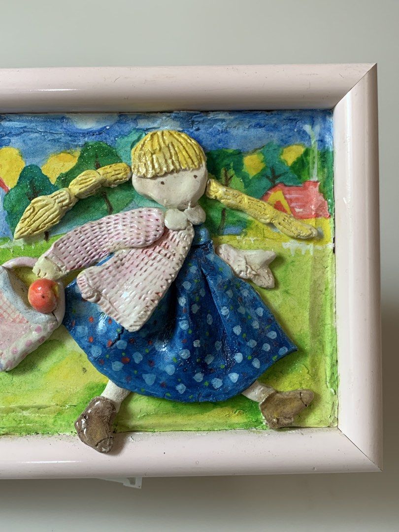 Handmade 3D Paper Clay Wall Art/ Frame (Category: Frames & Pictures) located in Tandag. Submitted by jeason_22 (Listing ID 1461623219, Image 3). Description: This charming handmade 3D paper clay wall art features a blonde-braided girl in a blue dress carrying a patterned bag in a vibrant pastoral landscape. Dimension: 5 x 6 inches Condition: may bak-bak sa left side bottom ( see photo ).
