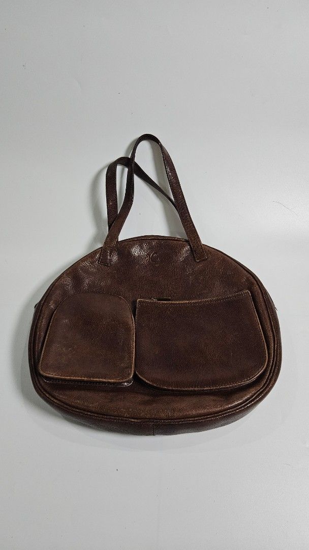 Hane Hands Brown Leather Shoulder Bag (Category: Shoulder Bags) located in Alfonso. Submitted by jbcamet (Listing ID 1461713316, Image 1). Description: - Brand: Hane Hands - Material: Genuine Leather - Color: Brown - Exterior Features: Two front pockets, one with a zipper - Interior Features: Suede lining, one zippered pocket - Condition: Shows a lovely patina from use, indicating character and quality - Straps: Comfortable for shoulder carrying 