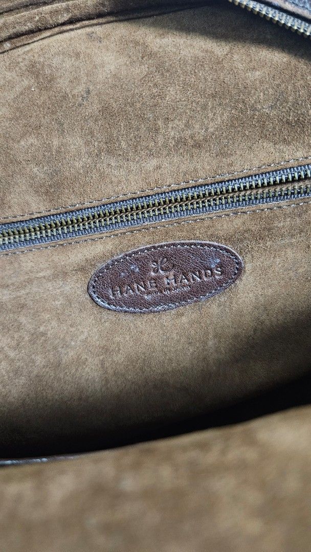 Hane Hands Brown Leather Shoulder Bag (Category: Shoulder Bags) located in Alfonso. Submitted by jbcamet (Listing ID 1461713316, Image 3). Description: - Brand: Hane Hands - Material: Genuine Leather - Color: Brown - Exterior Features: Two front pockets, one with a zipper - Interior Features: Suede lining, one zippered pocket - Condition: Shows a lovely patina from use, indicating character and quality - Straps: Comfortable for shoulder carrying 