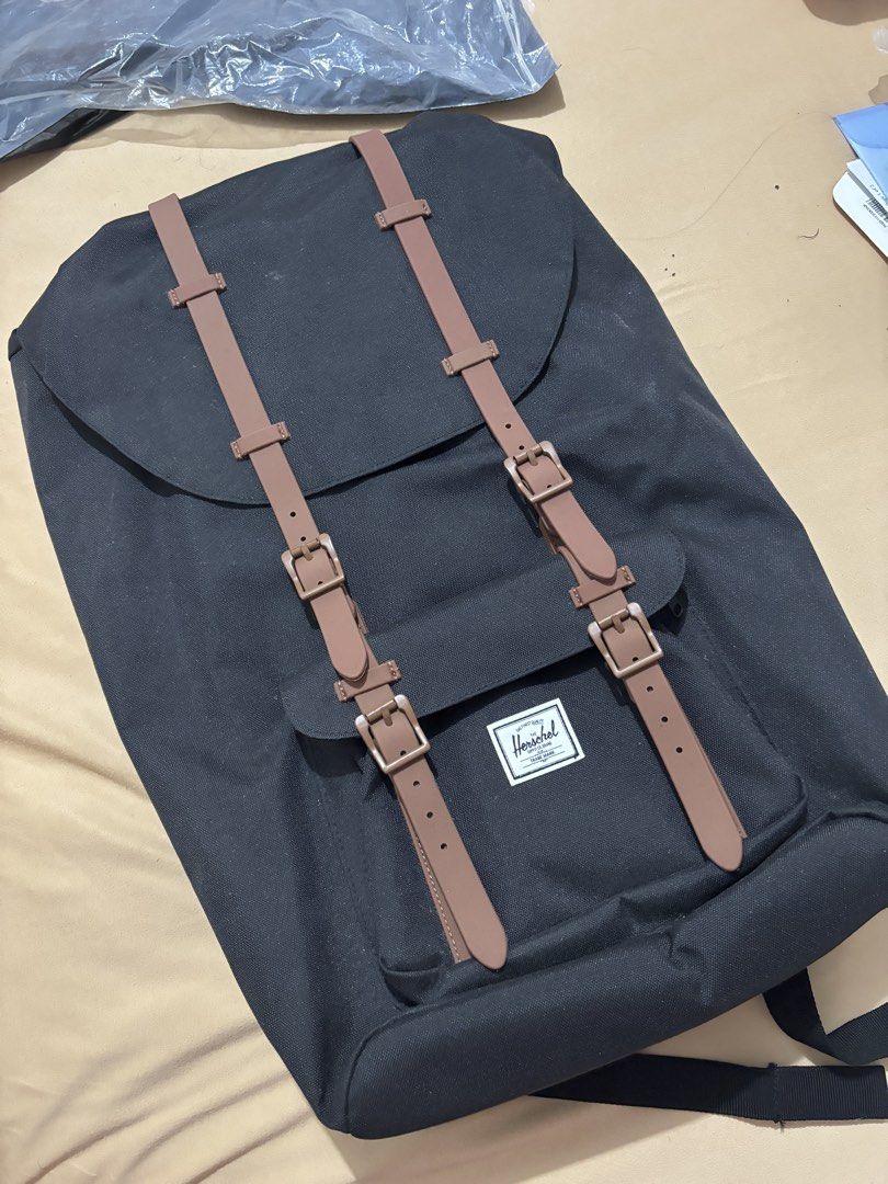 Herschel Little America Backpack Black (Category: Backpacks) located in Lucban. Submitted by quinsdollhouse (Listing ID 1461665766, Image 1). Description: - Classic black Herschel backpack - Brown faux leather straps with buckle closures - Signature red and white striped interior lining - Spacious main compartment for essentials - Adjustable padded shoulder straps for comfort - Just needs cleaning - Ideal for school, work, or everyday carry.