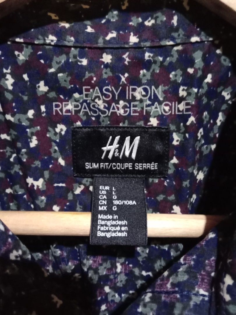 H&M Slim Fit Printed Shirt (Category: Tshirts & Polo Shirts ) located in San Fernando. Submitted by _luxielleph (Listing ID 1461797032, Image 2). Description: - H&M Slim Fit Shirt - Base Color: Dark Blue - Print: White and Purple Floral - Style: Long Sleeves, Button-Up Front - Material: Cotton and Polyester Blend - Feature: Easy Iron Fabric - Occasion: Casual or Smart-Casual Wear - Sizing: Please check the size label in the photos.
